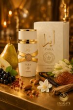 Flacon et boîte du parfum Lattafa Yara Moi blanc et or sur surface dorée, entourés de poire, cassis, poivre rose, jasmin, tubéreuse, amandes, vanille, bois de cachemire et résine d'ambre, logo Emirate Prestige